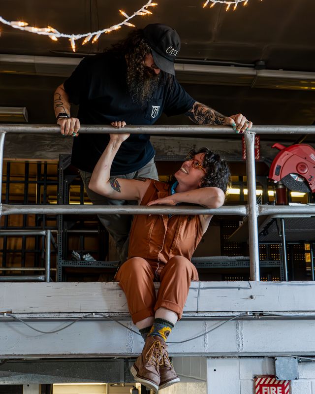 One team member leaning over a railing above another, both laughing